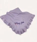 Lila renk tek kat müslin kumaştan üretilmiş fırfırlı bebek battaniyesi, kişiselleştirilebilir isim nakışlı model.