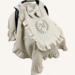 Bej tek kat müslin kumaştan, kapaklı ve kapak kenarları fırfırlı, tül pencereli, kişiselleştirilebilir puset örtüsü.