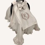 Bej tek kat müslin kumaştan fırfırlı, kapaklı puset örtüsü; tül pencereli ve kişiselleştirilebilir nakış detaylı model.