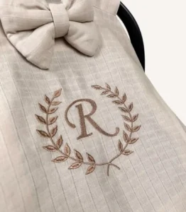 Bej tek kat müslin kumaştan fırfırlı, kapaklı puset örtüsü; tül pencereli ve kişiselleştirilebilir nakış detaylı model.