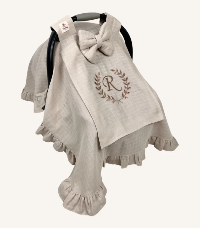 Bej tek kat müslin kumaştan fırfırlı, kapaklı puset örtüsü; tül pencereli ve kişiselleştirilebilir nakış detaylı model.