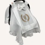 Beyaz tek kat müslin kumaştan fırfırlı, kapaklı puset örtüsü; tül pencereli ve kişiselleştirilebilir nakış detaylı model.