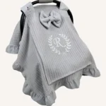 Gri örgü pike kumaştan, fırfırlı kenarlara sahip, fiyonklu kapaklı puset örtüsü.