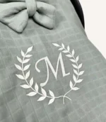 Haki tek kat müslin kumaştan fırfırlı, kapaklı puset örtüsü; tül pencereli ve kişiselleştirilebilir nakış detaylı model.