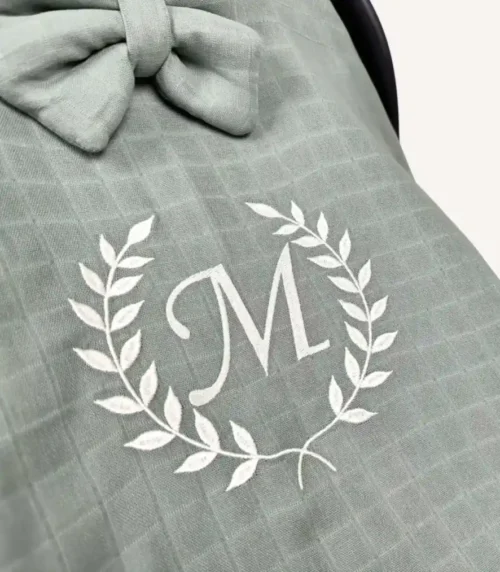 Haki tek kat müslin kumaştan fırfırlı, kapaklı puset örtüsü; tül pencereli ve kişiselleştirilebilir nakış detaylı model.