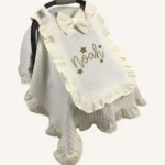 Krem örgü pike kumaştan fırfırlı, kapaklı puset örtüsü; tül pencereli ve kişiselleştirilebilir nakış detaylı model.