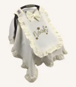 Krem örgü pike kumaştan fırfırlı, kapaklı puset örtüsü; tül pencereli ve kişiselleştirilebilir nakış detaylı model.