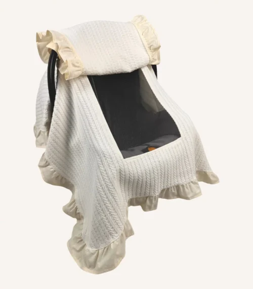 Krem örgü pike kumaştan fırfırlı, kapaklı puset örtüsü; tül pencereli ve kişiselleştirilebilir nakış detaylı model.