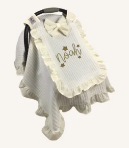 Krem örgü pike kumaştan fırfırlı, kapaklı puset örtüsü; tül pencereli ve kişiselleştirilebilir nakış detaylı model.