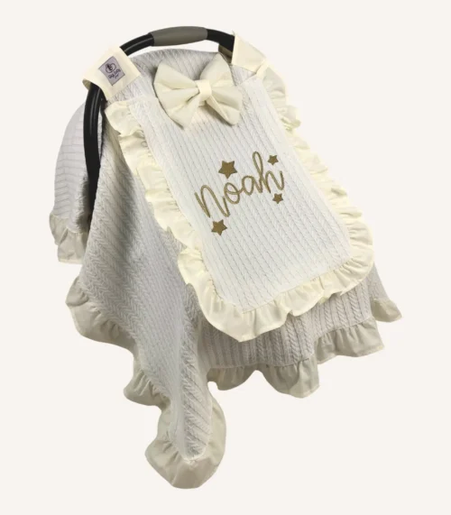 Krem örgü pike kumaştan fırfırlı, kapaklı puset örtüsü; tül pencereli ve kişiselleştirilebilir nakış detaylı model.