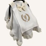 Krem örgü pike kumaştan, fırfırlı kenarlara sahip, fiyonklu kapaklı puset örtüsü.