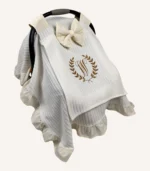 Krem örgü pike kumaştan, fırfırlı kenarlara sahip, fiyonklu kapaklı puset örtüsü.