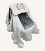 Krem örgü pike kumaştan, fırfırlı kenarlara sahip, fiyonklu kapaklı puset örtüsü.