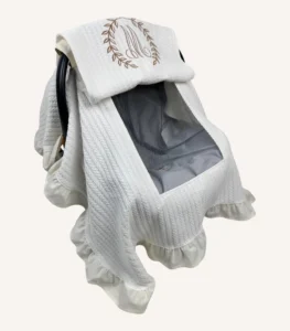 Krem örgü pike kumaştan, fırfırlı kenarlara sahip, fiyonklu kapaklı puset örtüsü.