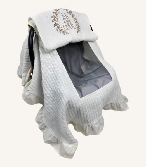 Krem örgü pike kumaştan, fırfırlı kenarlara sahip, fiyonklu kapaklı puset örtüsü.