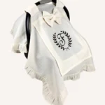 Krem tek kat müslin kumaştan fırfırlı, kapaklı puset örtüsü; tül pencereli ve kişiselleştirilebilir nakış detaylı model.