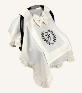 Krem tek kat müslin kumaştan fırfırlı, kapaklı puset örtüsü; tül pencereli ve kişiselleştirilebilir nakış detaylı model.