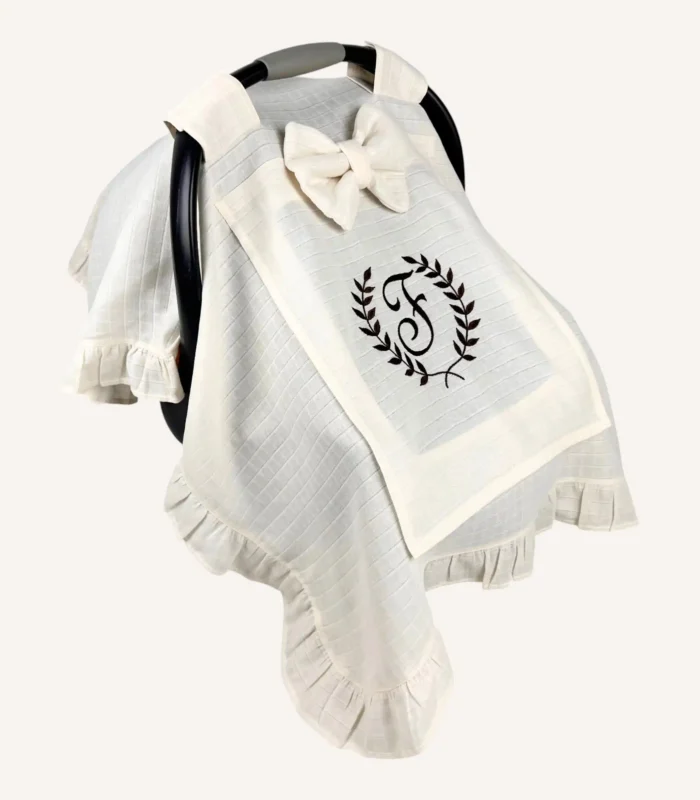 Krem tek kat müslin kumaştan fırfırlı, kapaklı puset örtüsü; tül pencereli ve kişiselleştirilebilir nakış detaylı model.