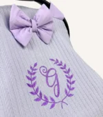 Lila örgü pike kumaştan, fırfırlı kenarlara sahip, fiyonklu kapaklı puset örtüsü.