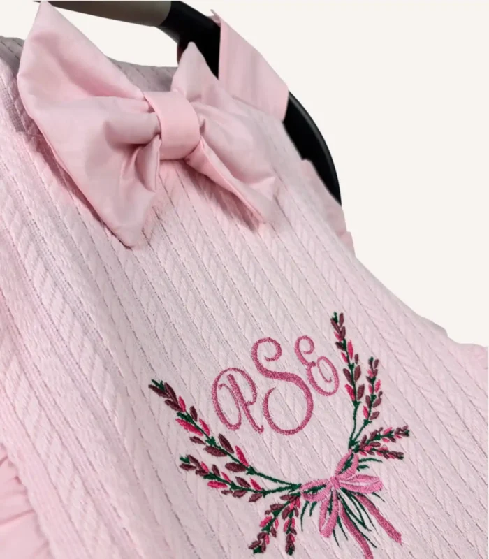 Pembe örgü pike kumaştan fırfırlı, kapaklı puset örtüsü; tül pencereli ve kişiselleştirilebilir nakış detaylı model.