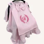 Pembe örgü pike kumaştan, fırfırlı kenarlara sahip, fiyonklu kapaklı puset örtüsü.