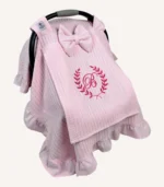 Pembe örgü pike kumaştan, fırfırlı kenarlara sahip, fiyonklu kapaklı puset örtüsü.