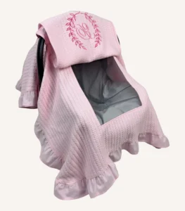 Pembe örgü pike kumaştan, fırfırlı kenarlara sahip, fiyonklu kapaklı puset örtüsü.