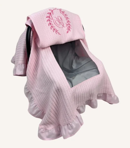 Pembe örgü pike kumaştan, fırfırlı kenarlara sahip, fiyonklu kapaklı puset örtüsü.