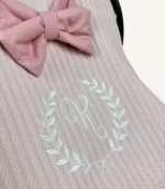 Pudra örgü pike kumaştan, fırfırlı kenarlara sahip, fiyonklu kapaklı puset örtüsü.