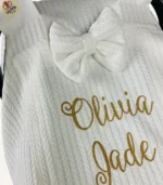 Beyaz örgü pike kumaştan, sade kapaklı, tül pencereli ve fiyonklu puset örtüsü.