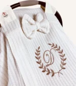 Krem örgü pike kumaştan, sade kapaklı, tül pencereli ve fiyonklu puset örtüsü.