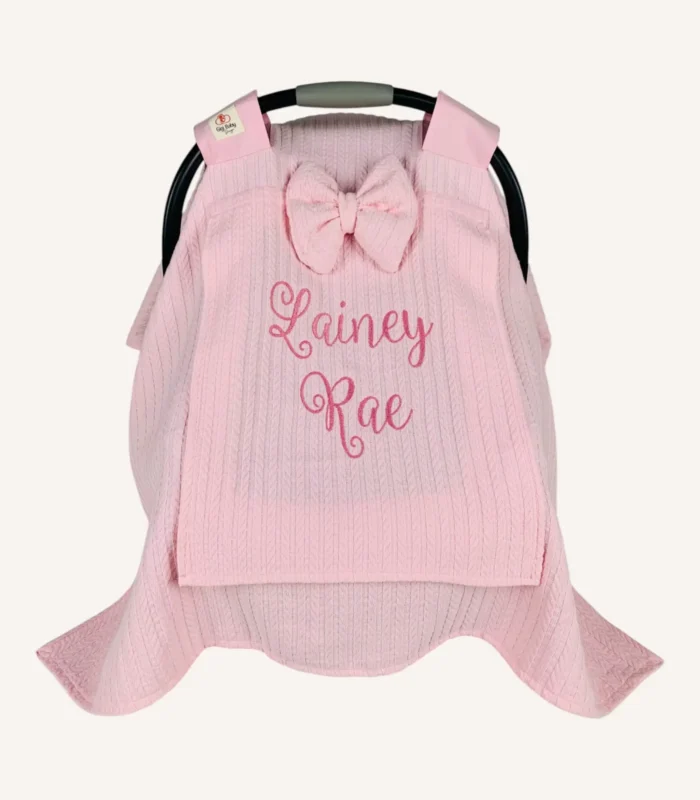 Pembe örgü pike kumaştan, sade kapaklı, tül pencereli ve fiyonklu puset örtüsü.