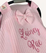 Pembe örgü pike kumaştan, sade kapaklı, tül pencereli ve fiyonklu puset örtüsü.