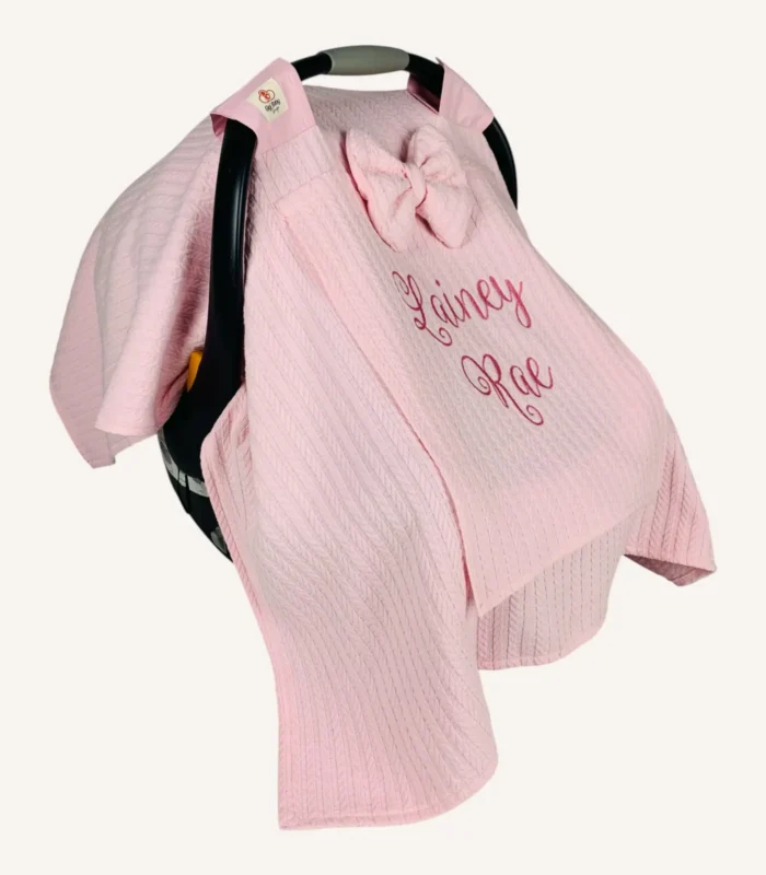 Pembe örgü pike kumaştan, sade kapaklı, tül pencereli ve fiyonklu puset örtüsü.