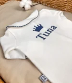 GOTS sertifikalı interlok kumaştan hazırlanan Organik Önden Çıtçıtlı Bebe Yakalı Kroşe İşlemeli Tulum ve Şapka Seti, kroşe detaylı bebe yakası, ayı kulaklı şapkası, kendinden eldivenli yapısı ve iç dikişsiz çift katlı patikleriyle prematüre ve 0-12 ay arası bebekler için tasarlanmıştır.
